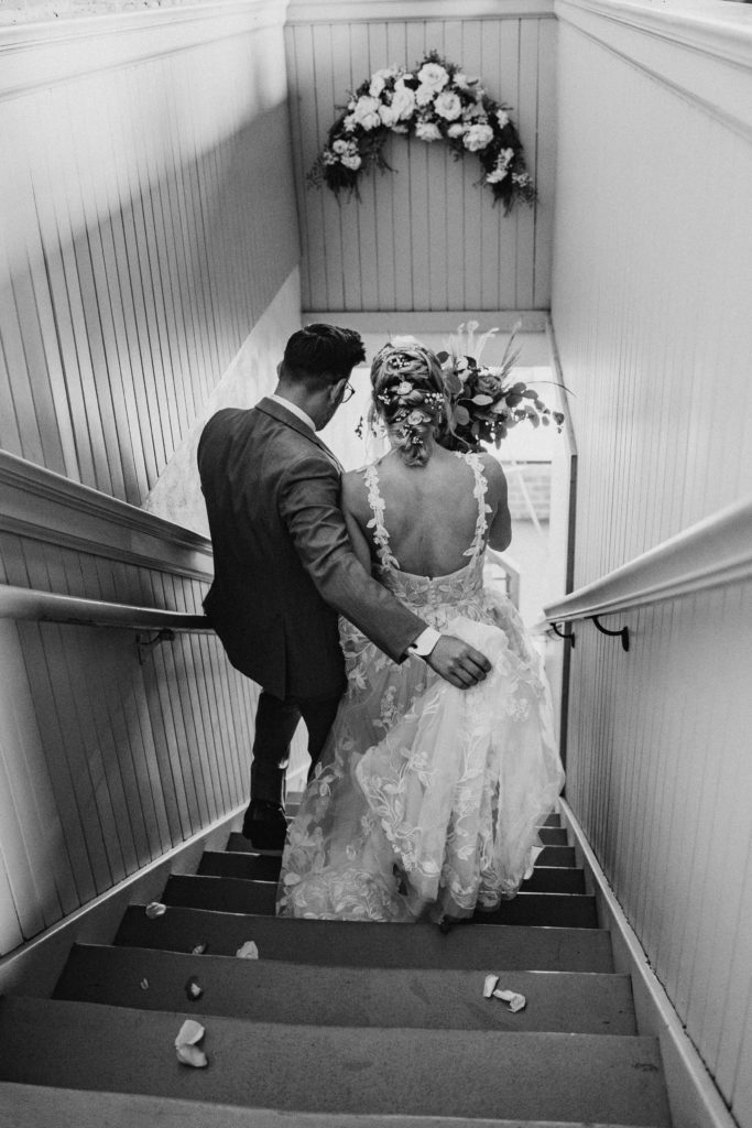 groom holding brides train down the stairs